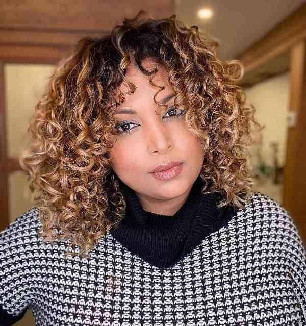 a caramel curly medium length bob with a darker root is layered internally to maximize your curls