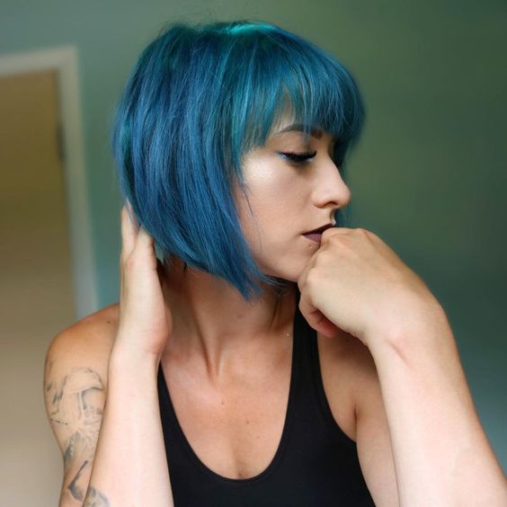 A catchy and bold teal angled chin length bob with bangs is a stylish idea for a statement like look