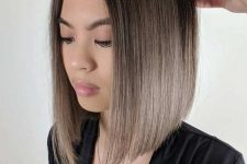 a cool mousy brown angled bob haircut with central parting and an ombre effect from darker root to mousy brown on the ends