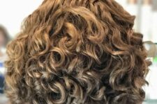 a curly light brunette asymmetrical bob is a layered haircut that preserves a natural curl pattern