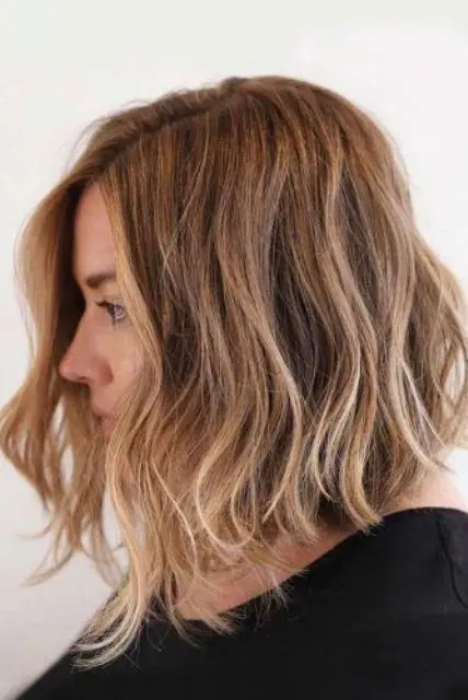 a light brown angled bob with honey balayage, side part, waves and texture is a chic and catchy solution
