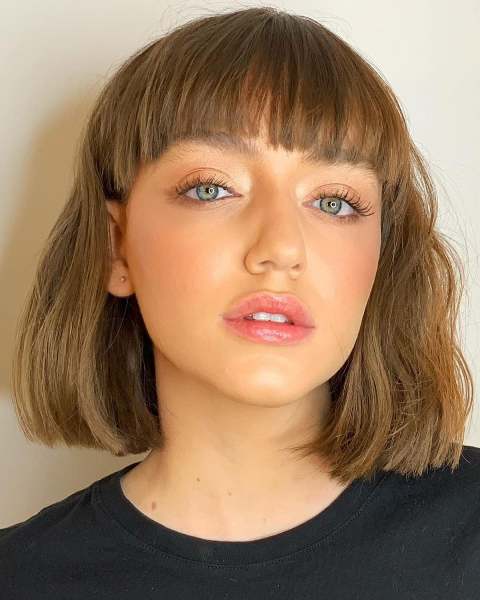 a light brown to caramel blunt bob on thick hair, with bangs and waves is a stylish solution