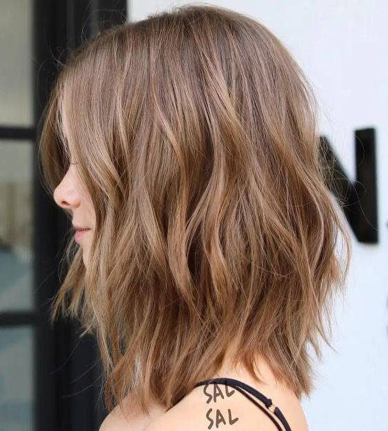 a light brunette layered long bob with some highlights for a texture, waves for a messy and voluminous look
