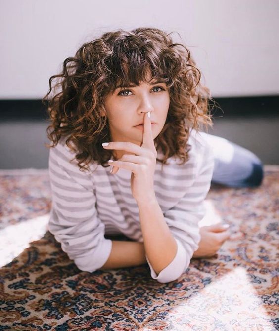 a long curly burnette bob with shorter layers in the front and short bangs is an amazing idea to try for your curly hair