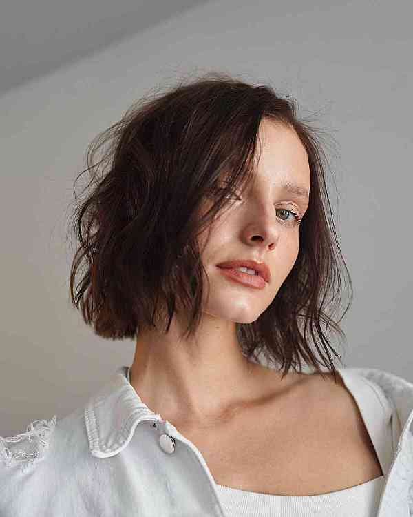 a modern and soft blunt bob in brown looks sophisticated and waves and a texturized weight line create a lovely look