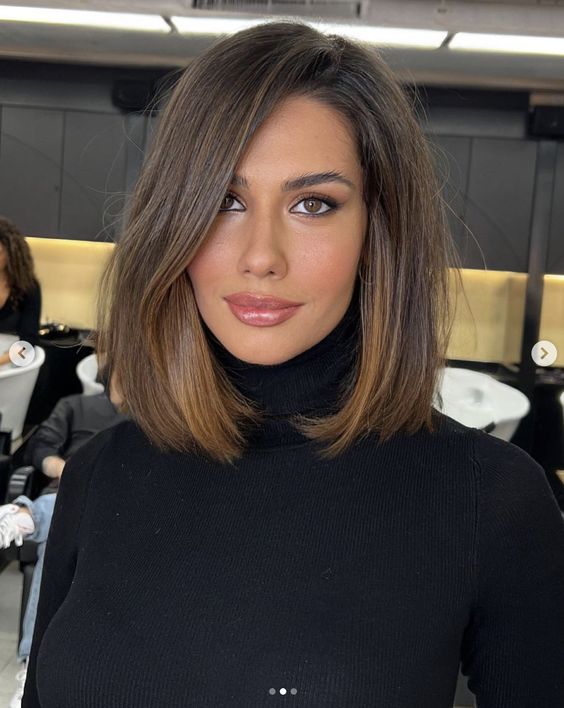a pretty mousy brown collarbone bob with a bit of caramel highlights, side part and a lot of volume looks very chic
