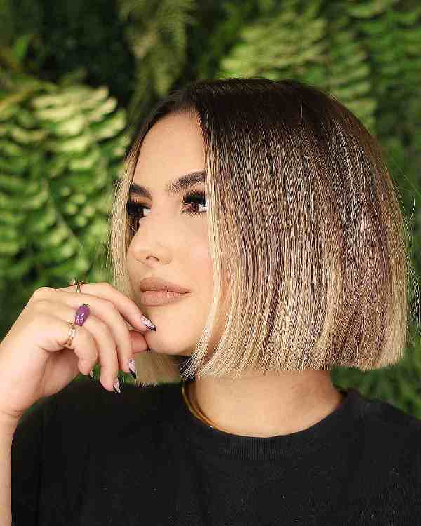 a short blunt bob with dark roots and blonde highlights and money piece is a very stylish and glam idea
