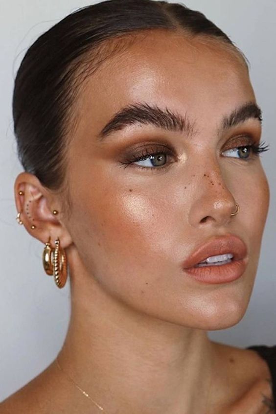 a summer bronze makeup with a nude lip, blush and highlighter, fluffy eyebrows, brown smokeys for summer parties