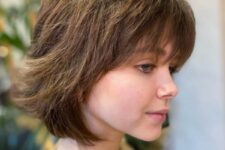 a textured medium length brown wolf cut with bangs is a gorgeous take on the haircut that looks soft and cute