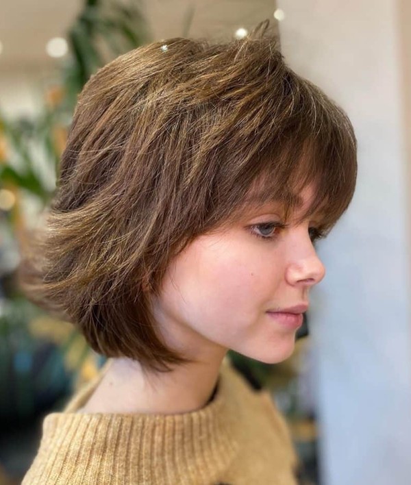 a textured medium length brown wolf cut with bangs is a gorgeous take on the haircut that looks soft and cute