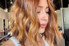 an auburn and orange wavy long bob with layers and a shiny finish is a super bold and catchy idea to try