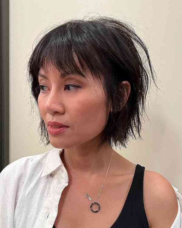 an edgy choppy French bob in black, with wispy bangs is cool and chic idea that is low-maintenance