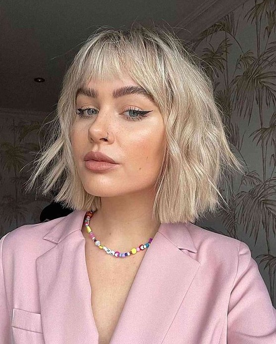 an eye-catchy textural and wavy blonde choppy bob with wispy bangs is a cool idea that looks trendy and fresh