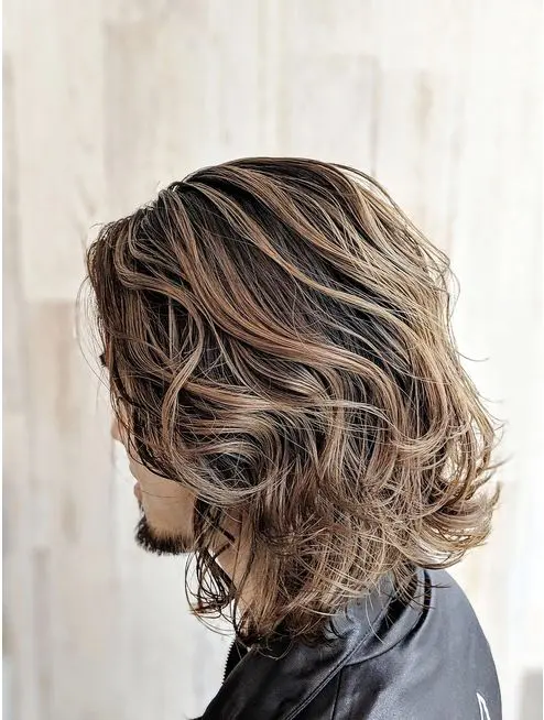 beautiful brown shoulder-length wavy hair with caramel balayage that imitates sun-bleached locks looks jaw-dropping