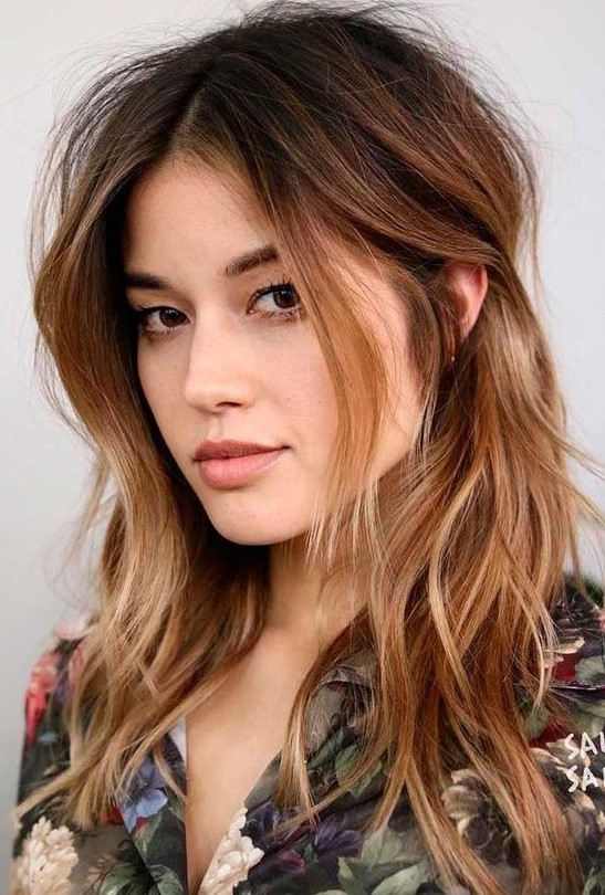 dark brown root plus ombre caramel ends and messy waves plus layered bangs looks bold and catchy
