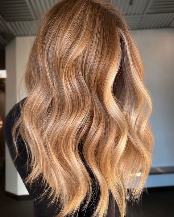 El fantástico cabello largo y castaño claro con balayage y ondas rubio dorado y miel es una idea elegante y pegadiza para el verano.