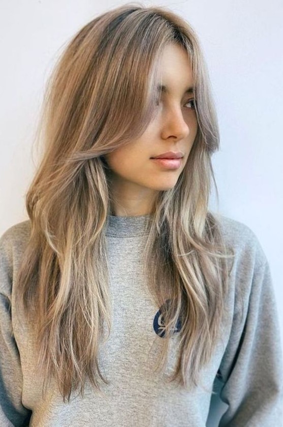 long mushroom blonde hair with a slight balayage and long curtain bangs that perfectly frame the face
