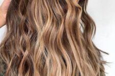 long wavy brunette hair with gold blonde balayage is a pretty idea for summer that doesn’t require much maintenance