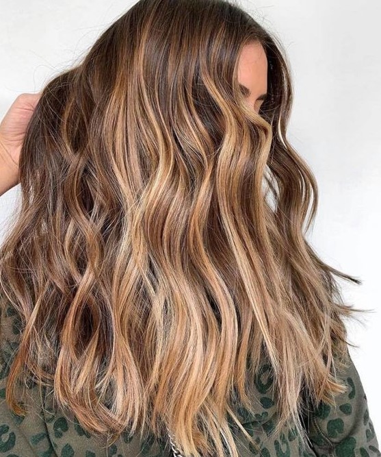 long wavy brunette hair with gold blonde balayage is a pretty idea for summer that doesn't require much maintenance