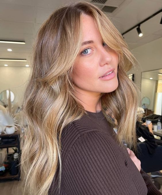 long wavy light brown hair with blonde highlights and a chunky chin-length money piece looks chic and beautiful