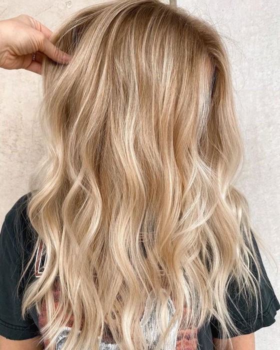 Lovely blonde hair with a darker root, with gold and icy blonde balayage and waves loosk truly beach like and cool