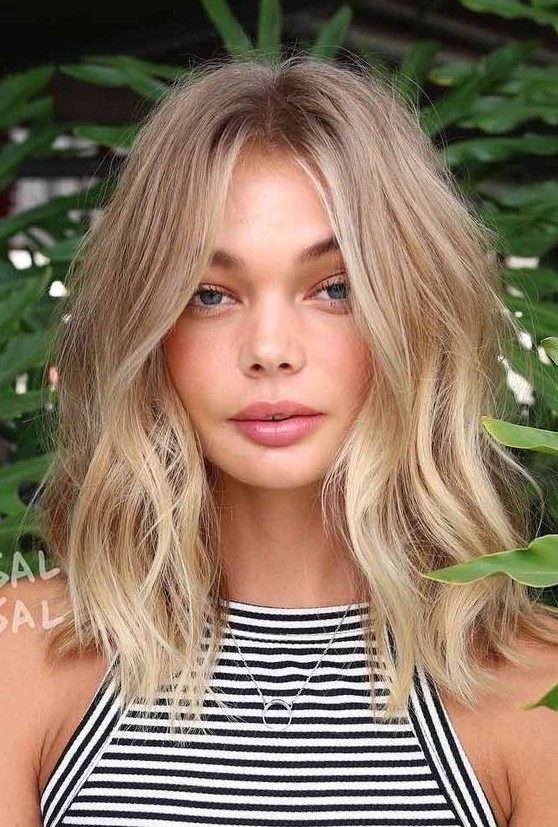 medium length honey blonde hair with beach balayage and messy waves is a cool idea for a summer feel