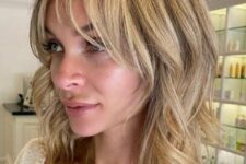 a blonde medium length choppy layered haircut with side and wispy bangs paired looks cool, fresh and very modern
