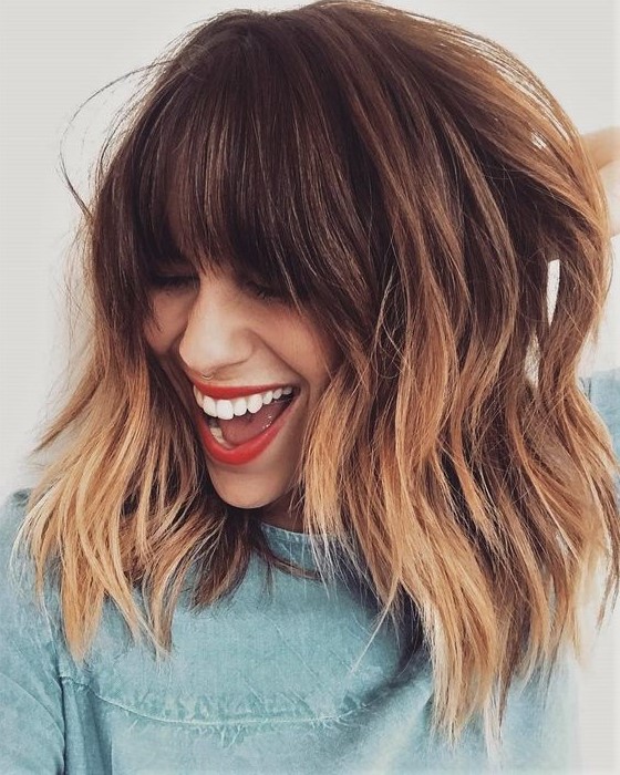 a brown layered long bob with copper highlights and with classic fringe bangs is a super chic and bold idea