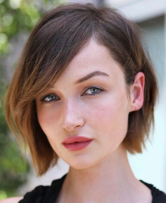 A chin length brown bob with caramel ombre, side parting and side bangs is a chic anad catchy solution