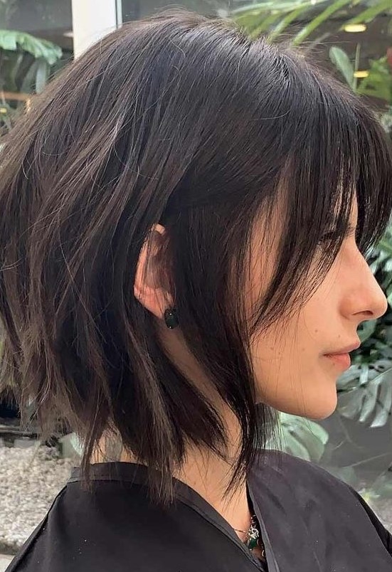 a choppy dark brunette bob with bangs and slight waves is a bold and chic idea