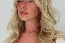 a classy wavy blonde hairstyle with a lot of dimension and Bardot bangs is a cool and chic idea to rock