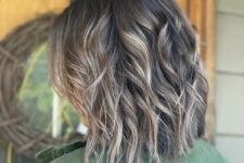 a dark brown medium haircut with bronde highlights and waves plus choppy layers that bring a lot of dimension