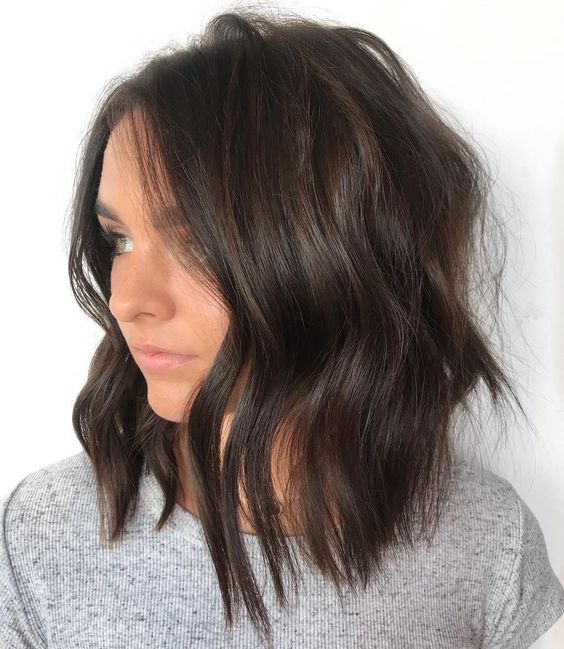 a dark brown wavy shaggy and choppy haircut with side parting is a stylish and modern idea to try