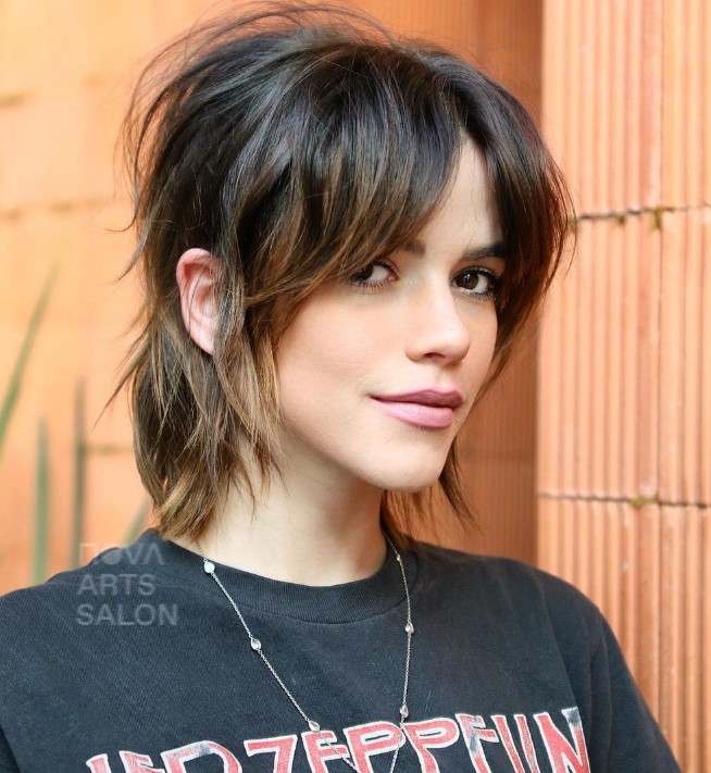 a dark brunette tucked shaggy bob with curtain bangs, caramel highlights and a bit of messy dimension is wow