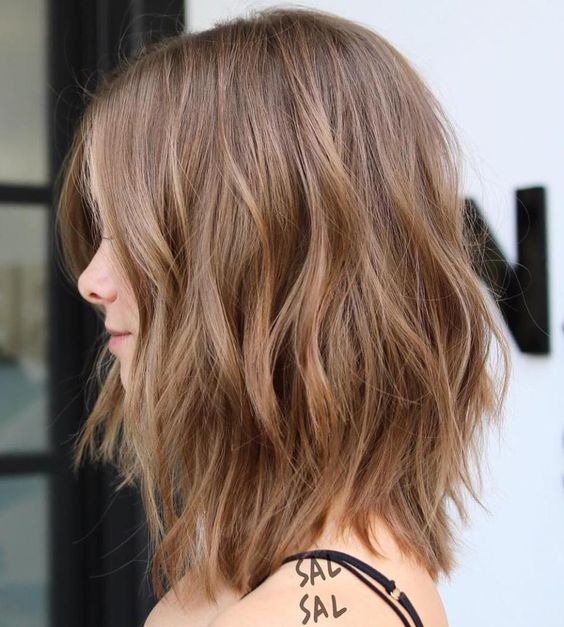 a delicate and soft brown choppy long bob with subtle highlights and waves and face-framing layers is cool