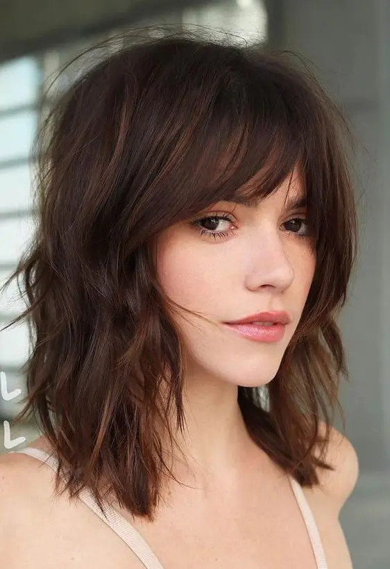 a gorgeous shaggy and wavy dark chestnut long bob with a 70s inspired curtain fringe