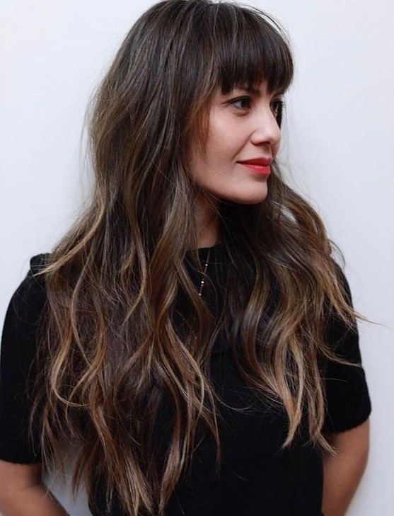 a long layered haircut with balayage and eyebrow-skimming fringe bangs for an effortless look