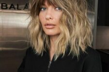 a lovely and dimensional outgrown bob haircut with a darker root, blonde balayage and a fringe is wow
