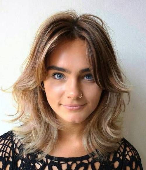 a pretty and lovely light burnette shaggy bob with blonde balayage, central parting, side bangs and waves