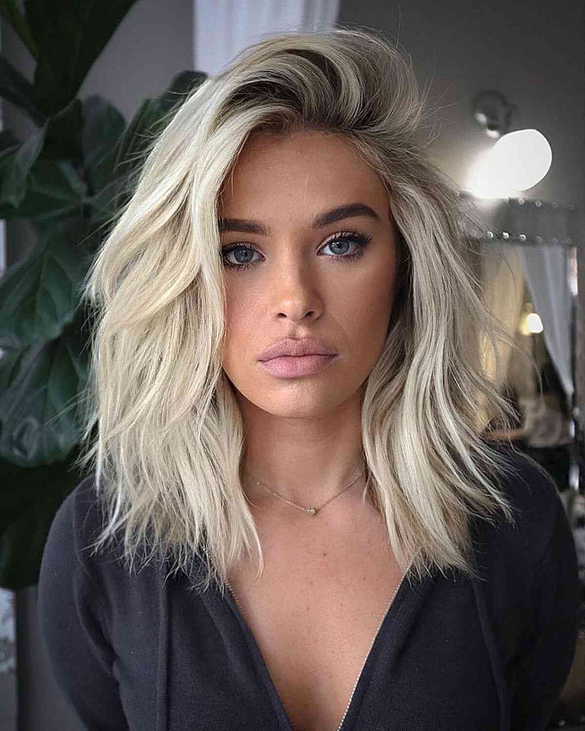 an icy blonde medium length haircut with voluminous choppy layers that create dimension fits any face shape and hair type