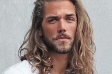 beautiful long wavy hair pushed aside and in a natural shade plus a full beard are a cool Viking-like look