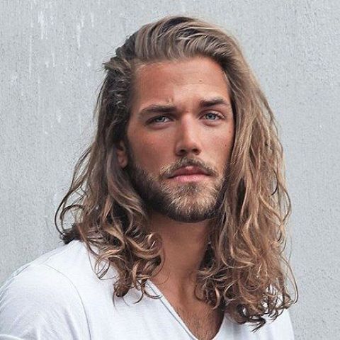 Beautiful long wavy hair pushed aside and in a natural shade plus a full beard are a cool Viking like look