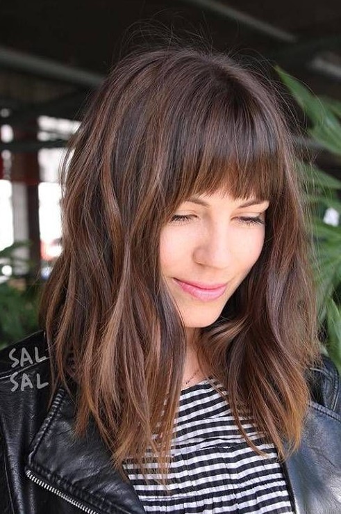 Dark brown hair with a lighter chestnut balayage, messy waves and Birkin bangs   wispy ones