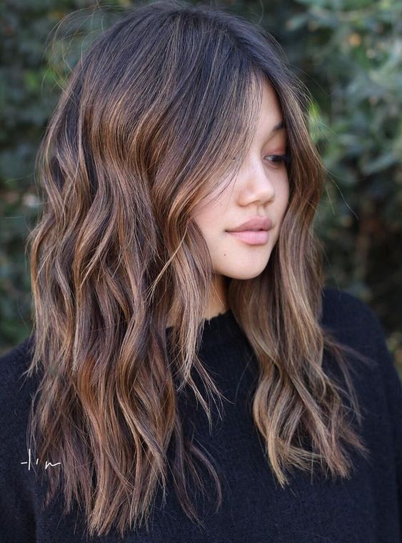 dark brown wavy hair with caramel balayage and central parting looks gogeous and is easy to maintain