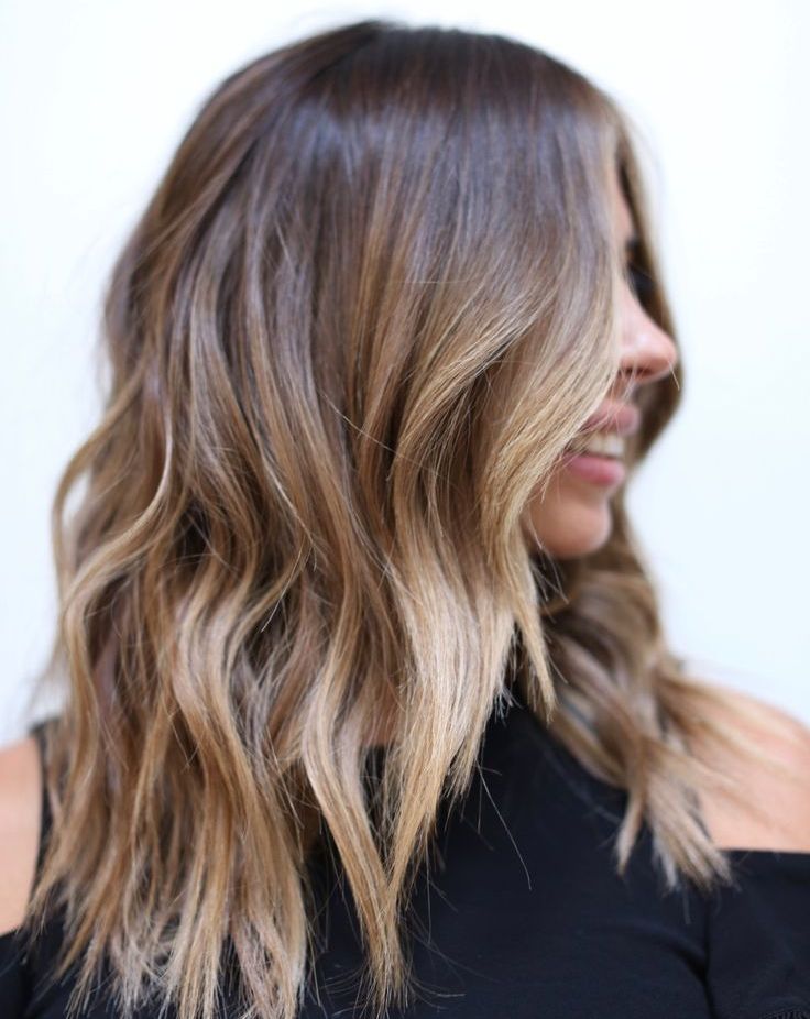dark brunette hair with lighter balayage and a money piece plus slight beach waves looks cool and bold