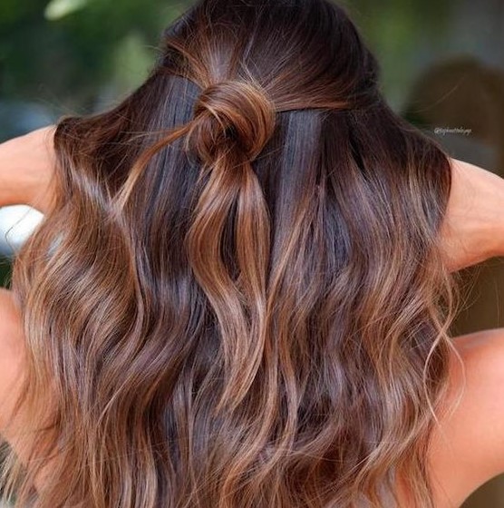dark chestnut hair with waves and a knot and with caramel balayage to give the hair more dimension and texture