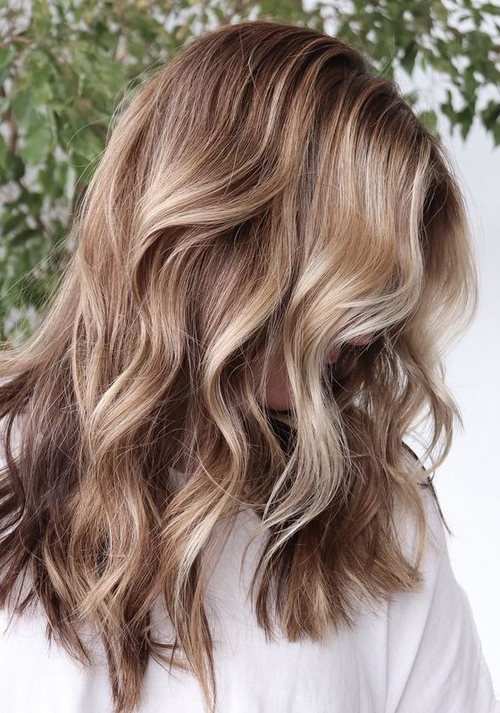 Light brunette hair with blonde balayage and waves looks relaxed, chic and beach inspired