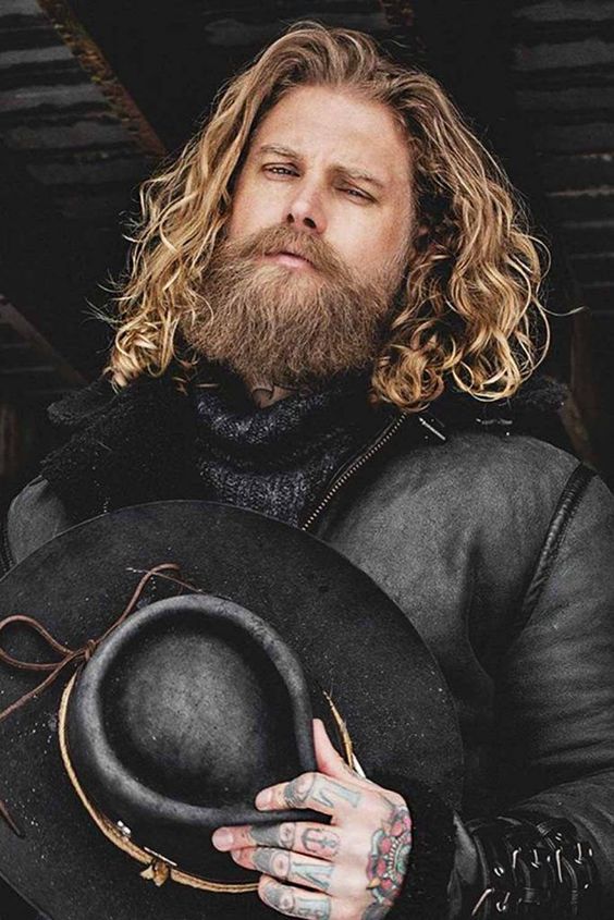 Long blonde wavy hair plus a full long beard are a cool and chic combo for a Viking style look