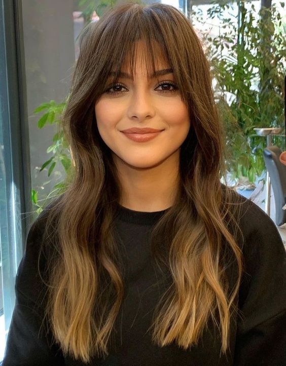 long brunette wavy hair with an ombre touch and fringe bangs is a chic and cool idea to rock right now