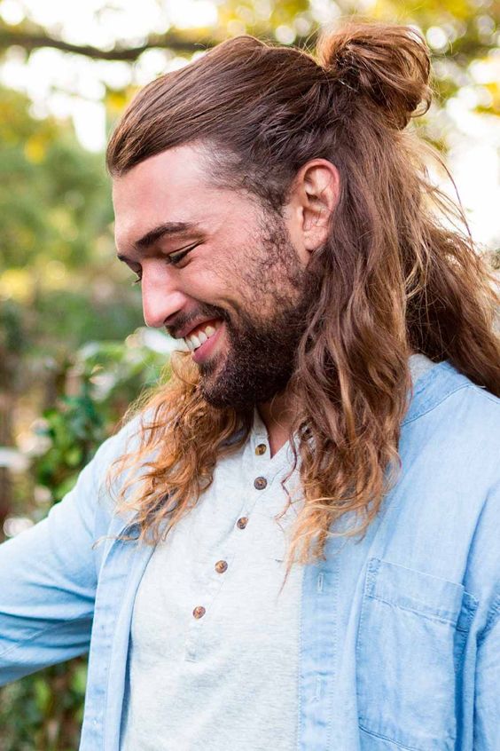 long brunette wavy hair with some golden and honey blonde highlights and ombre touches, a man bun and a messy top is a cool idea